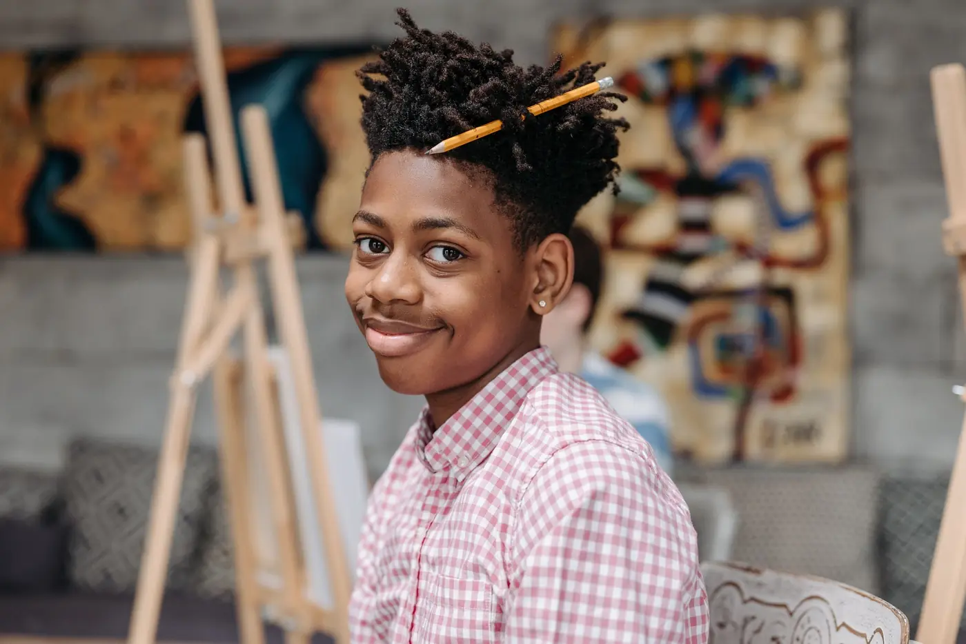 A teenage boy smiling in a bright art room